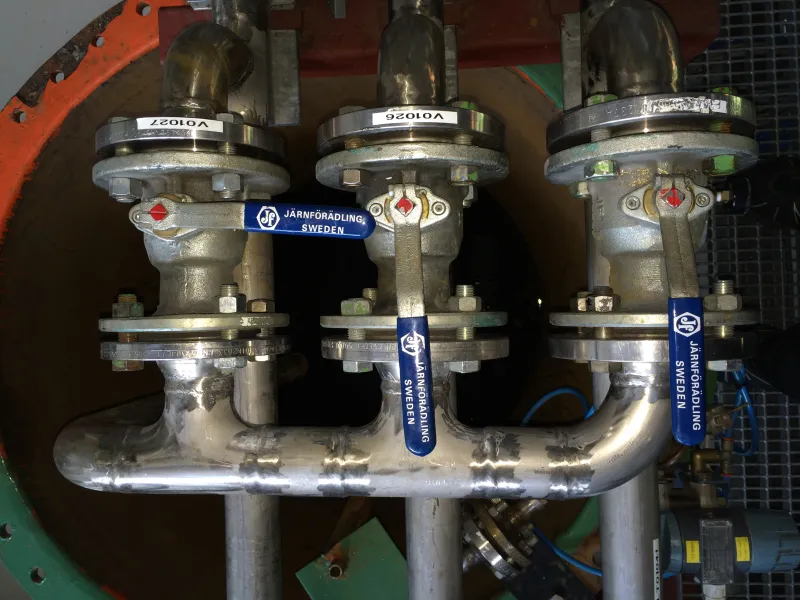 Three flanged valves with blue operating handles in a pipe assembly